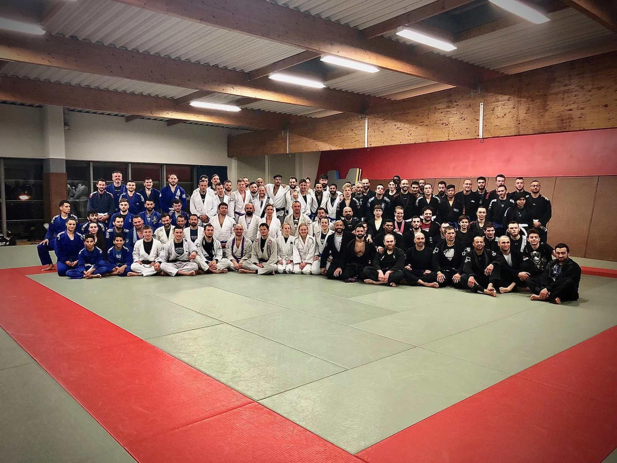 Photo de groupe du club dans la grande salle, en kimonos blancs, bleus et noirs
